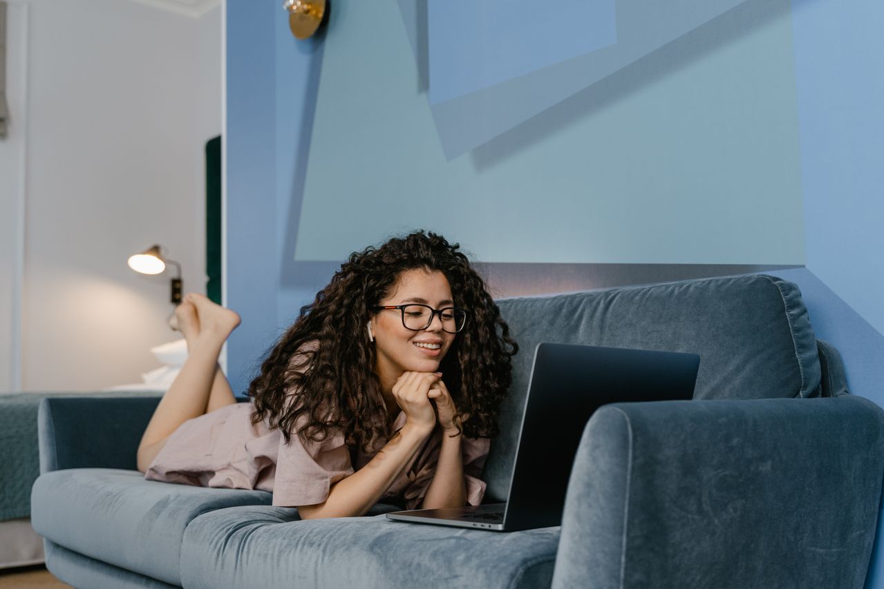 A woman laying on her couch and smiling during a random video chat